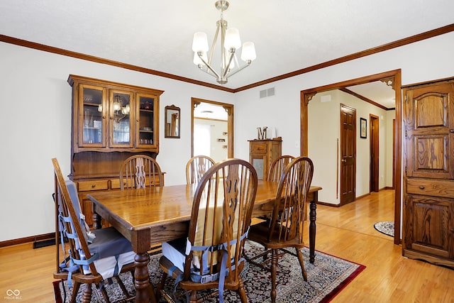 dining space with crown molding, a chandelier, and light hardwood / wood-style flooring