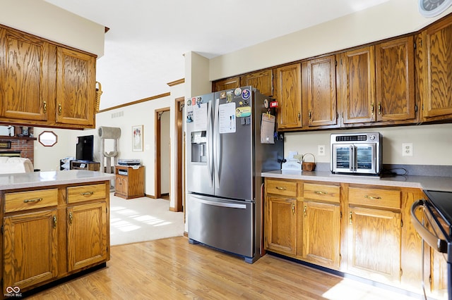 kitchen featuring stainless steel appliances, ornamental molding, and light wood-type flooring