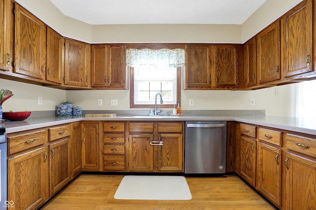 kitchen with stainless steel dishwasher, sink, and light wood-type flooring