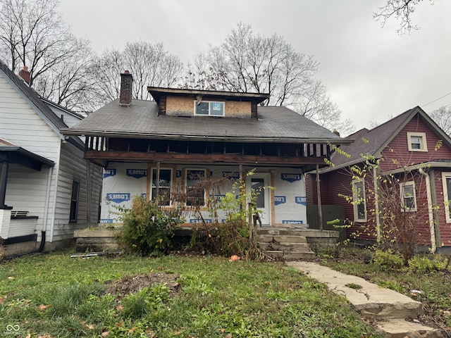 bungalow-style home with a front yard and covered porch