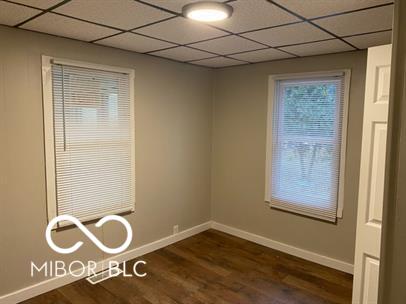 spare room featuring dark hardwood / wood-style flooring and a paneled ceiling