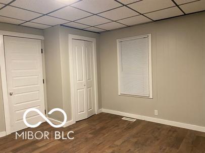 unfurnished bedroom featuring dark hardwood / wood-style flooring, a paneled ceiling, and a closet