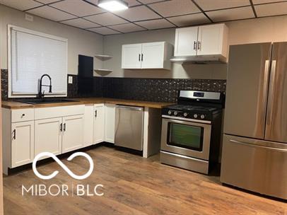 kitchen featuring sink, light hardwood / wood-style flooring, white cabinets, stainless steel appliances, and a drop ceiling