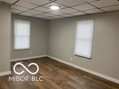 empty room featuring a paneled ceiling and dark hardwood / wood-style floors