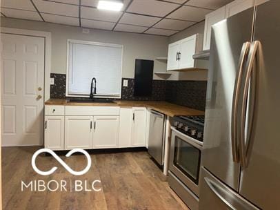 kitchen with sink, dark hardwood / wood-style floors, white cabinets, stainless steel appliances, and backsplash