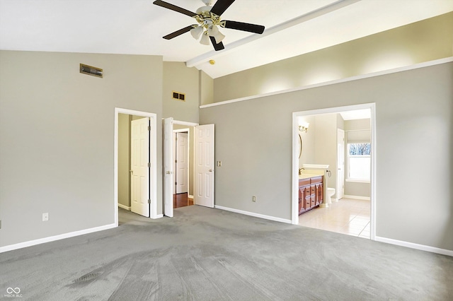 unfurnished bedroom with beamed ceiling, high vaulted ceiling, light carpet, and ensuite bath