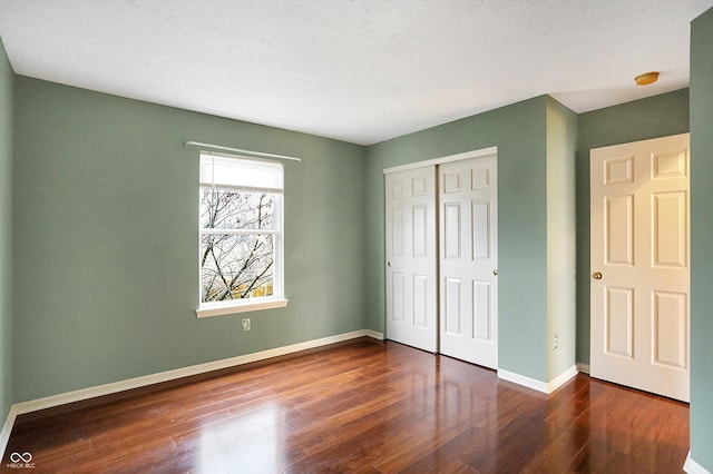 unfurnished bedroom with a closet, dark hardwood / wood-style floors, and a textured ceiling