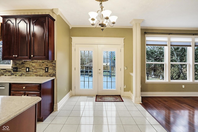 entryway with french doors, light tile patterned flooring, crown molding, an inviting chandelier, and decorative columns