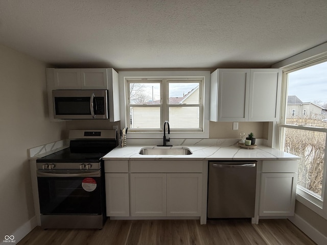 kitchen featuring appliances with stainless steel finishes, a wealth of natural light, sink, and white cabinets