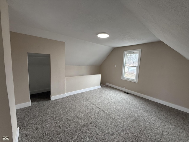 bonus room featuring lofted ceiling, carpet floors, and a textured ceiling