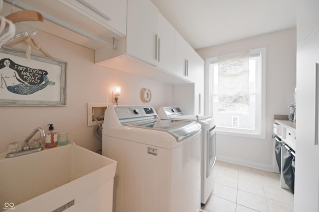 washroom with cabinets, sink, washing machine and dryer, and light tile patterned floors