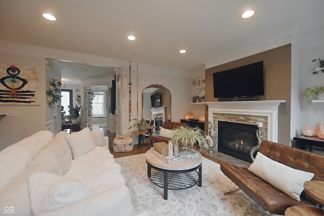 living room featuring ornamental molding, a stone fireplace, and wood-type flooring