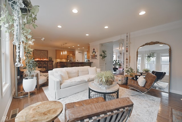 living room with crown molding, light hardwood / wood-style floors, and a notable chandelier