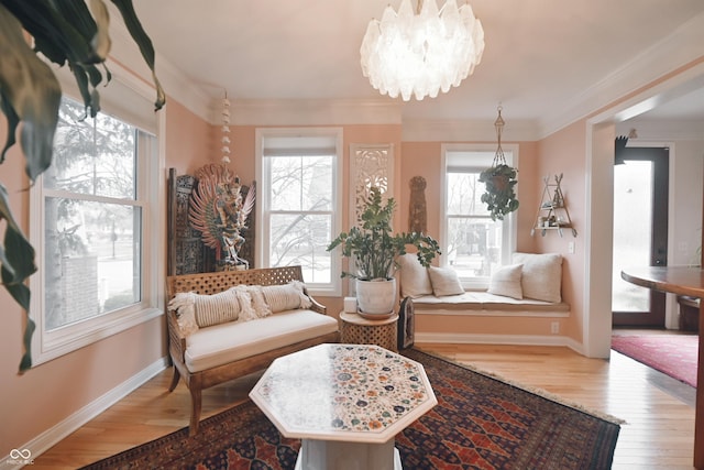 sitting room with a notable chandelier, wood-type flooring, and ornamental molding