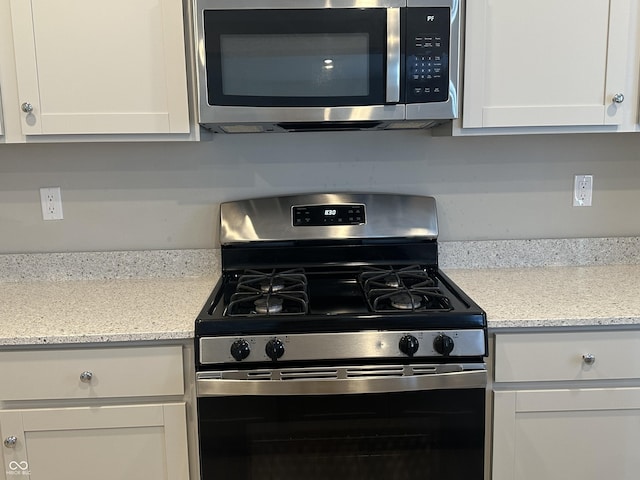 kitchen with white cabinetry, light stone countertops, and gas stove