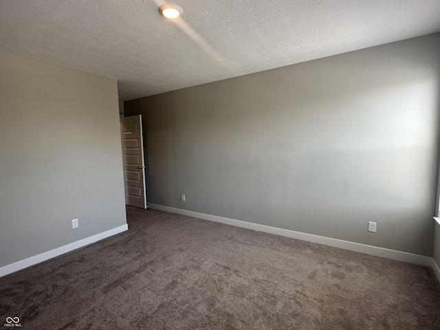 empty room with carpet floors and a textured ceiling