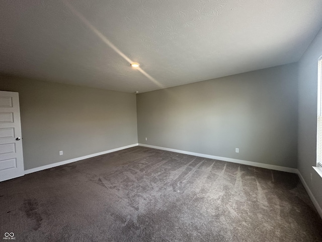 carpeted empty room featuring a textured ceiling