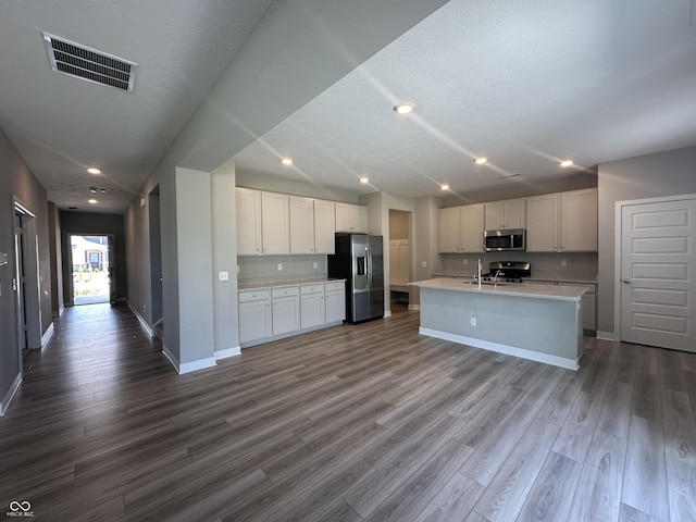 kitchen featuring white cabinetry, an island with sink, appliances with stainless steel finishes, and hardwood / wood-style flooring