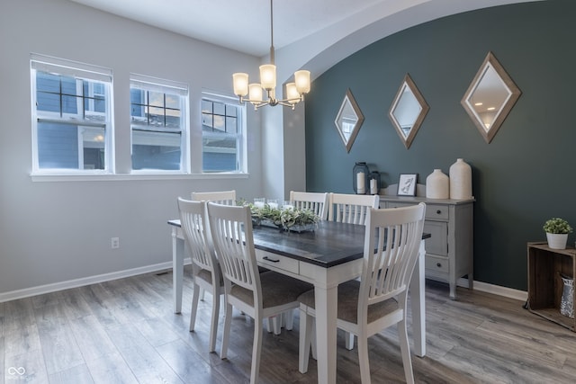 dining area with baseboards, an inviting chandelier, and wood finished floors