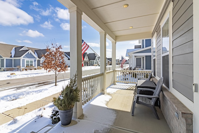 snow covered patio with a porch and a residential view