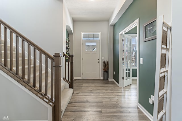 entryway with stairs, baseboards, and wood finished floors