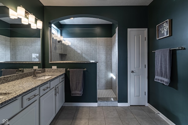 full bath featuring tile patterned floors, baseboards, a sink, double vanity, and a walk in shower