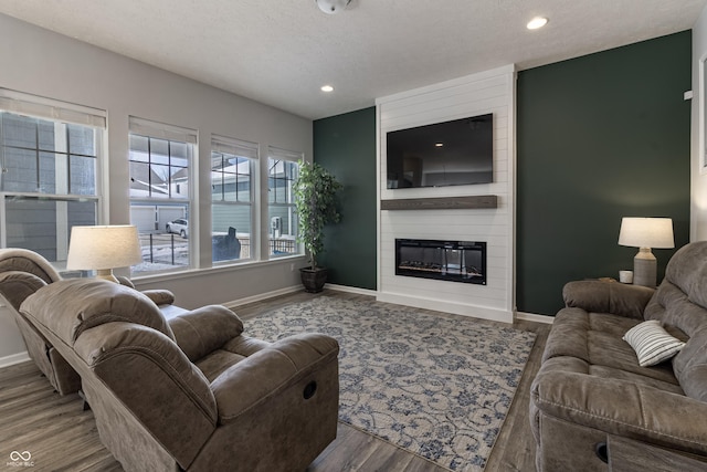 living room featuring a large fireplace, baseboards, recessed lighting, and wood finished floors