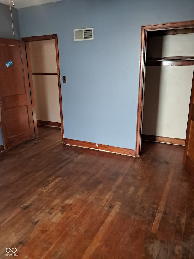 unfurnished bedroom with dark hardwood / wood-style floors and a closet