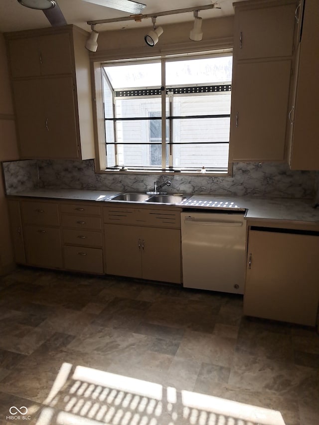 kitchen featuring white dishwasher, sink, and backsplash