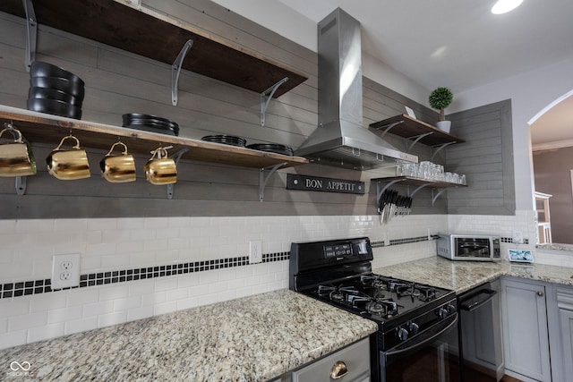 kitchen with black gas stove, gray cabinetry, backsplash, light stone counters, and island exhaust hood