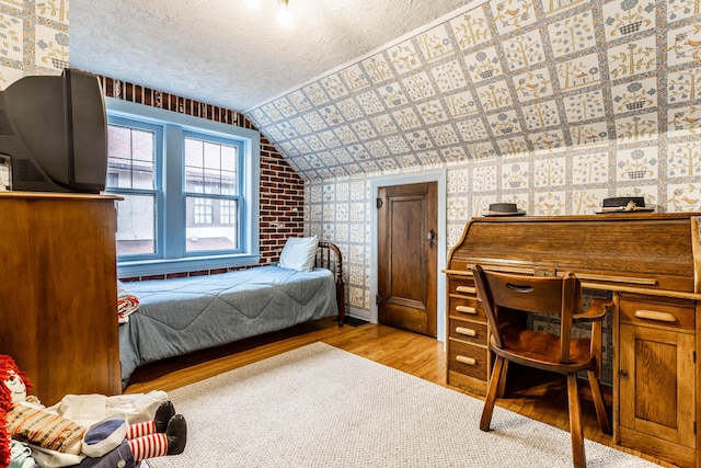 bedroom with vaulted ceiling, light hardwood / wood-style flooring, and a textured ceiling