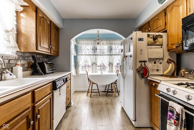 kitchen with sink, backsplash, white appliances, and light hardwood / wood-style floors