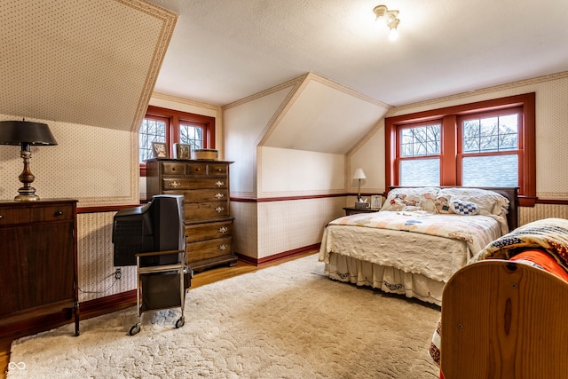 bedroom featuring vaulted ceiling, a textured ceiling, and light hardwood / wood-style floors