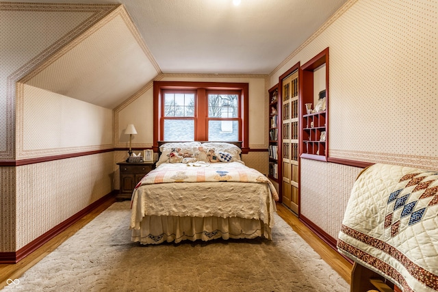 bedroom with crown molding, wood-type flooring, and vaulted ceiling