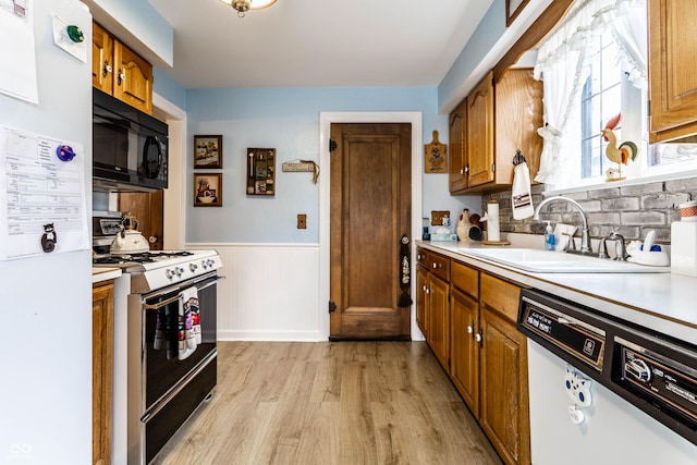 kitchen featuring white appliances, sink, and light wood-type flooring