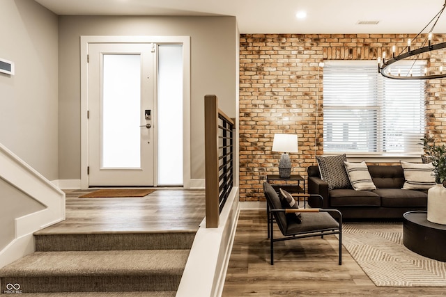 entryway with hardwood / wood-style floors, a healthy amount of sunlight, and brick wall