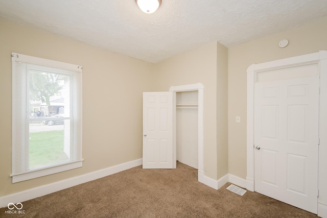 unfurnished bedroom featuring a closet, a textured ceiling, and carpet