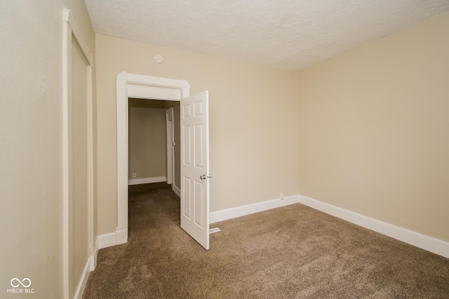 carpeted empty room with a textured ceiling