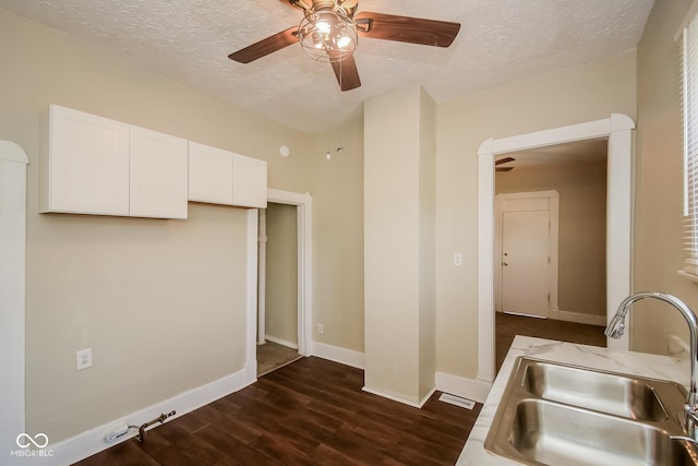 kitchen with sink, a textured ceiling, dark wood-type flooring, and white cabinets