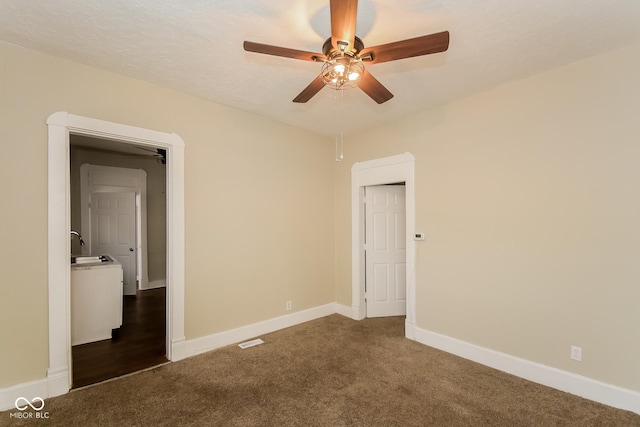 empty room with ceiling fan, sink, dark carpet, and a textured ceiling