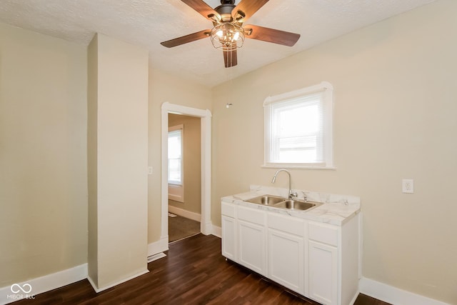 kitchen featuring sink, dark wood-type flooring, white cabinets, and a textured ceiling