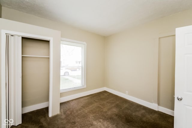 unfurnished bedroom featuring a closet and dark colored carpet