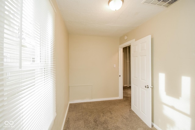 hallway featuring carpet flooring and a textured ceiling