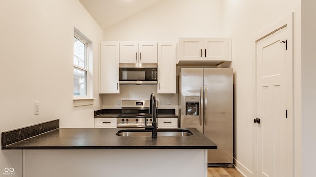 kitchen featuring sink, vaulted ceiling, appliances with stainless steel finishes, kitchen peninsula, and white cabinets