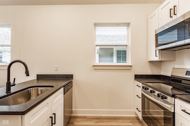 kitchen with plenty of natural light, appliances with stainless steel finishes, sink, and white cabinets