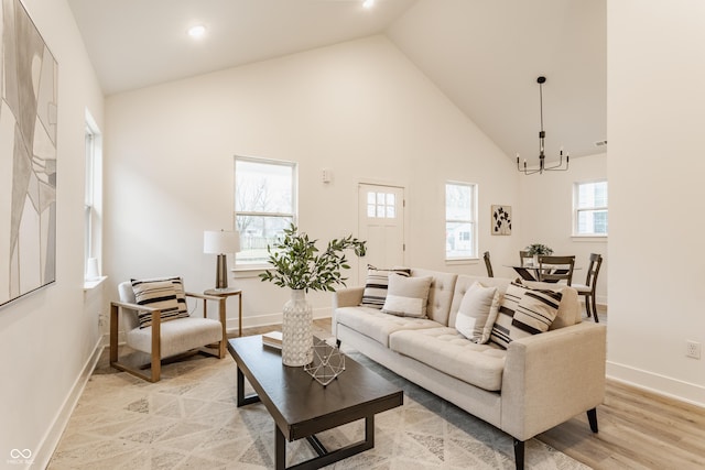 living room with a notable chandelier, high vaulted ceiling, and light hardwood / wood-style flooring