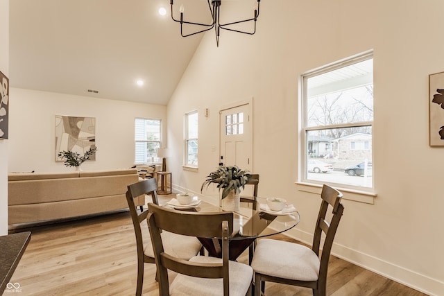 dining space with high vaulted ceiling, light hardwood / wood-style floors, and a chandelier