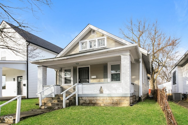 bungalow with covered porch, a front yard, and central air condition unit