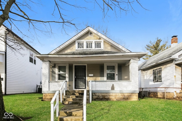 bungalow-style home featuring cooling unit, covered porch, and a front lawn