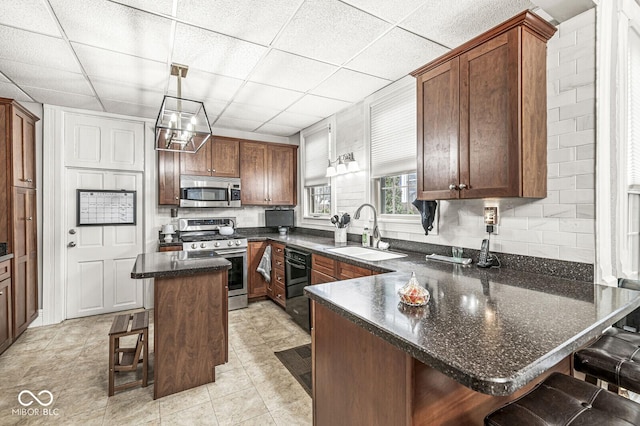 kitchen featuring a breakfast bar, sink, appliances with stainless steel finishes, kitchen peninsula, and pendant lighting